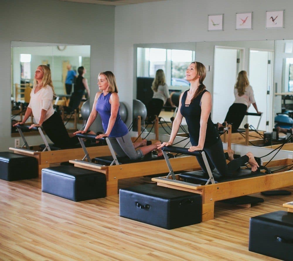 Three clients on oak reformers during a group class.